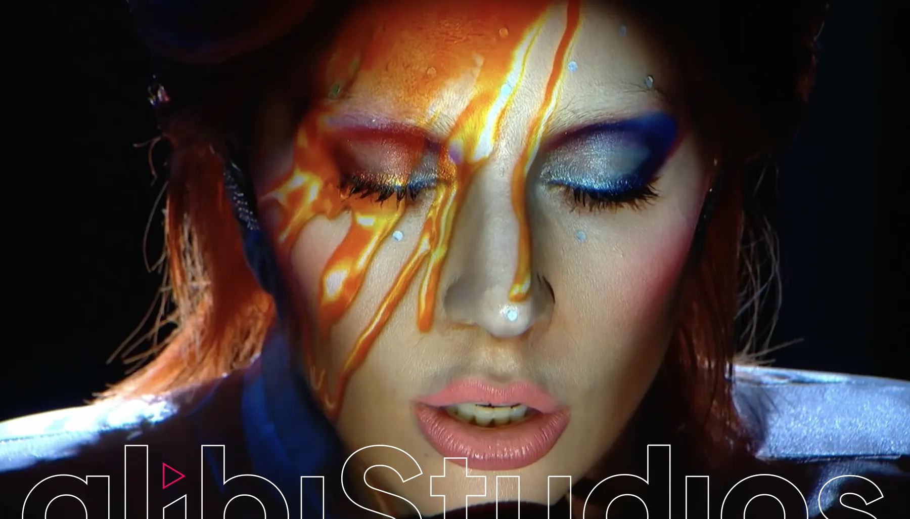 Alibi Studios brand image: a face in bright stage make-up with the studio wordmark